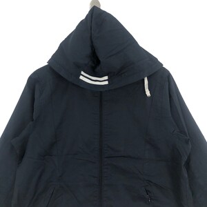 K&ouml;nnte beinhalten: Eine marineblaue Kapuzenjacke mit einem wei&szlig;en Streifen-Detail an der Kapuze. Die Jacke hat einen Rei&szlig;verschluss und eine Kapuze mit Kordelzug.