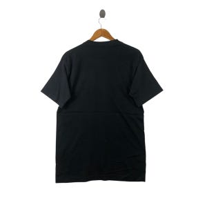 May include: A black short-sleeved t-shirt hanging on a wooden hanger. The t-shirt is plain with no visible graphics or text.