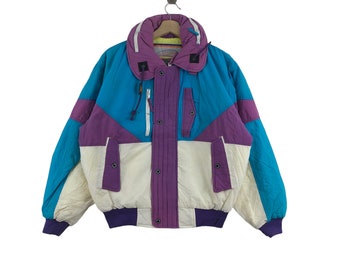 May include: A vintage ski jacket with a color block design in purple, blue, and white. The jacket has a zipper closure and a high collar.