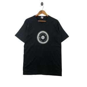 May include: Black t-shirt with a white graphic of a vinyl record with the text "Original Album Series" and "The Beatles" printed on it.
