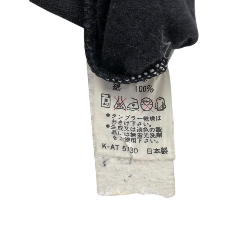 May include: A black garment tag with Japanese text and care symbols. The tag reads "綿 100%" indicating 100% cotton. It also includes washing instructions and the text "K-AT 5130 日本製".
