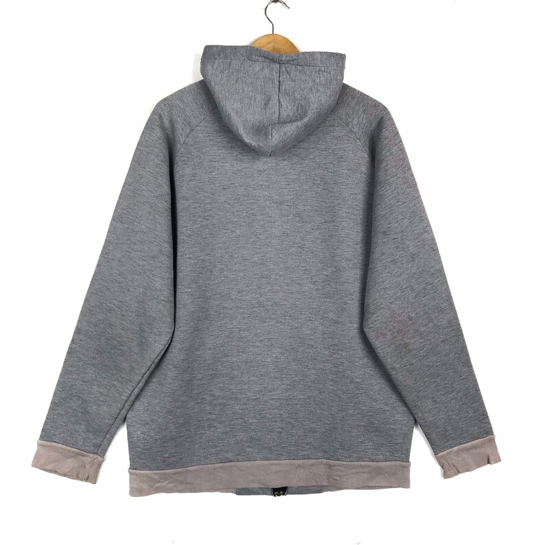 以下が含まれることがあります： ジッパー留めと裾と袖にライトグレーのトリムが付いたグレーのフード付きスウェットシャツです。