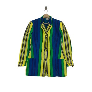 May include: A colorful striped blazer in shades of yellow, green, and blue. The jacket features long sleeves, a collared neckline, and three black buttons down the front. It is hanging on a wooden hanger against a white background.
