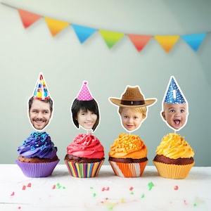 K&ouml;nnte beinhalten: Vier Cupcakes mit farbenfrohem Zuckerguss und Gesichtern obenauf, dekoriert f&uuml;r eine Geburtstagsfeier. Jeder Cupcake hat eine andere Zuckergussfarbe: Lila, Rot, Orange und Gelb. Die Gesichter tragen Partyh&uuml;te und einen Cowboyhut. Im Hintergrund h&auml;ngt ein farbenfrohes Banner.