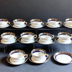 May include: Set of 10 teacups and saucers with a cobalt blue and gold design. The cups and saucers are made of white porcelain and have a delicate floral pattern.