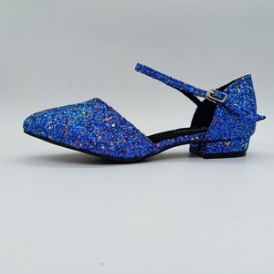 May include: Blue glitter heeled shoes with an ankle strap and buckle fastening.
