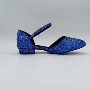 May include: Blue glitter ankle strap heeled shoes with a low block heel.