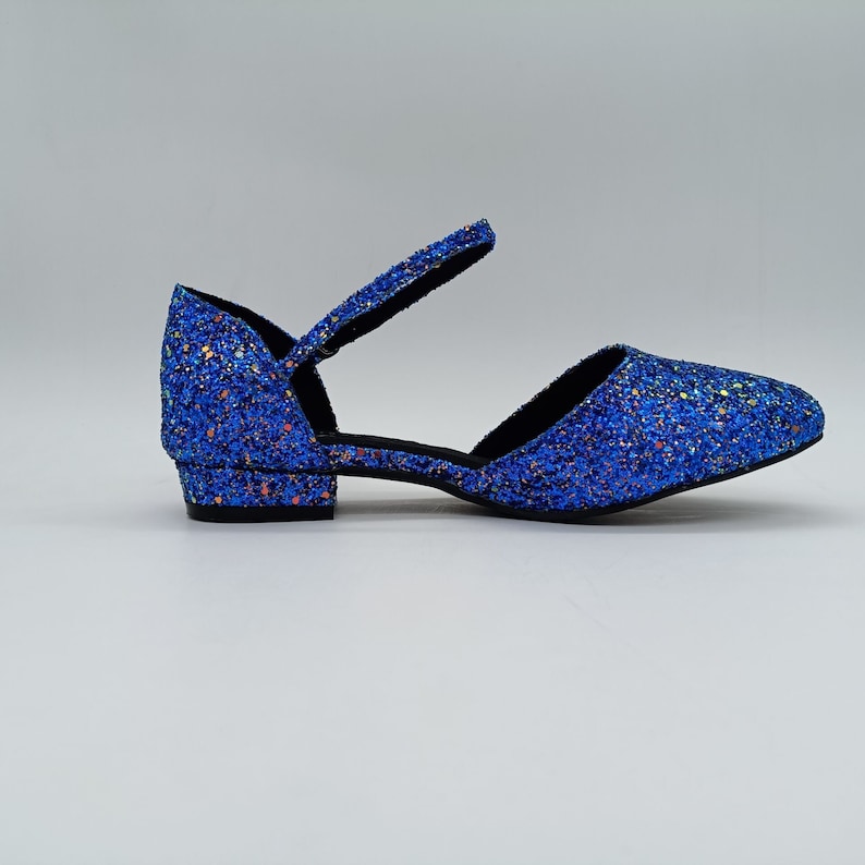 May include: Blue glitter ankle strap heeled shoes with a low block heel.