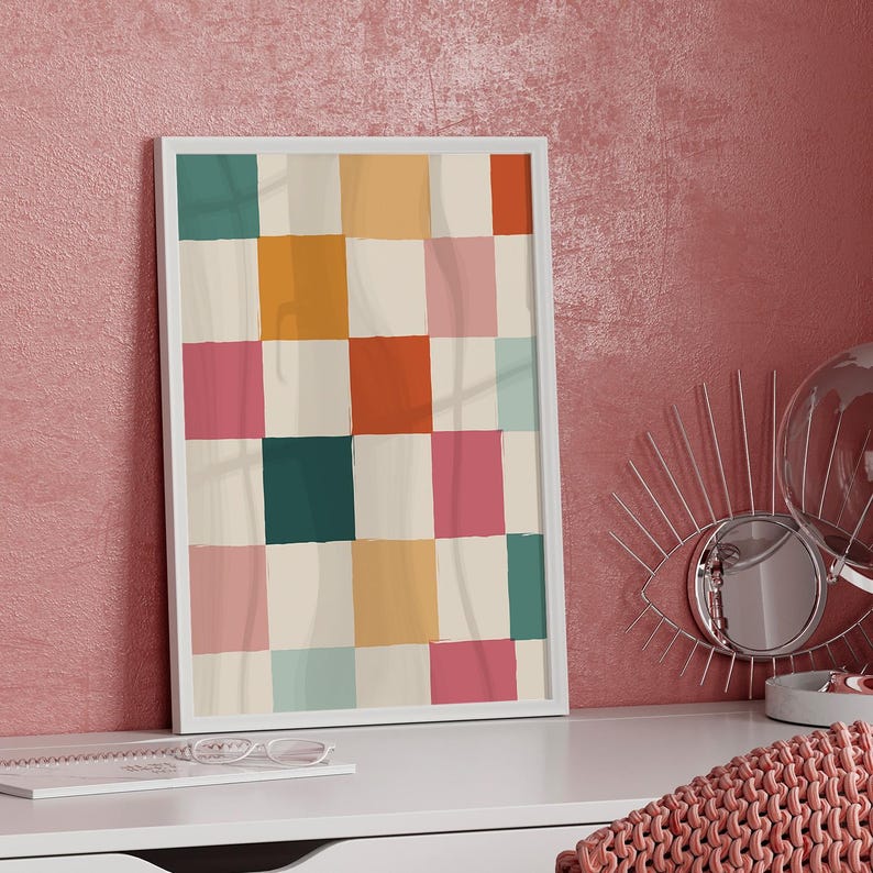 K&ouml;nnte beinhalten: Ein gerahmter abstrakter Kunstdruck mit einem Rastermuster aus farbigen Quadraten. Die Quadrate sind in den Farbt&ouml;nen T&uuml;rkis, Rosa, Orange, Gelb und Creme gehalten und erzeugen ein lebendiges Design. Das Kunstwerk wird in einem wei&szlig;en Rahmen pr&auml;sentiert.