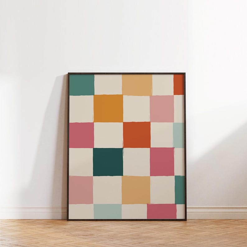 K&ouml;nnte beinhalten: Ein gerahmtes Kunstwerk mit einem farbenfrohen Schachbrettmuster. Die Quadrate sind in verschiedenen Farben wie T&uuml;rkis, Orange, Rosa und Creme bemalt, mit sichtbaren Pinselstrichen. Das Kunstwerk lehnt an einer wei&szlig;en Wand auf einem Holzboden.