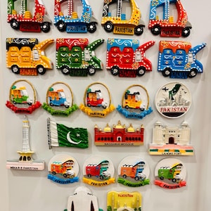 Pode incluir: Uma coleção de vinte e três ímanes de frigorífico coloridos com vários motivos paquistaneses, incluindo riquexós em miniatura, camiões, a Mesquita Badshahi, o Forte de Lahore, Minar-e-Pakistan, Mazar-e-Quaid e a bandeira nacional, todos com a etiqueta Pakistan.