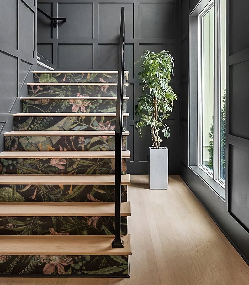 May include: A set of stairs with a black railing and a floral patterned wallpaper on each step. The stairs are in a room with a large window and a potted plant.