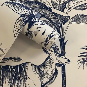 May include: A roll of wallpaper featuring a dark blue ink illustration on a cream background. The design depicts a detailed antelope standing among large tropical palm leaves and foliage, rendered in a classic etched or woodcut style.