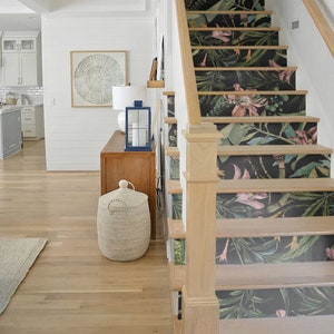 May include: A wooden staircase with a floral wallpaper design. The wallpaper features pink flowers, green leaves, and black stems. The staircase is made of light wood and has a white railing.