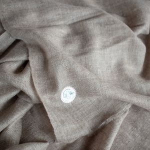 May include: A soft, light brown cashmere scarf with a small white tag that says "100% Cashmere".