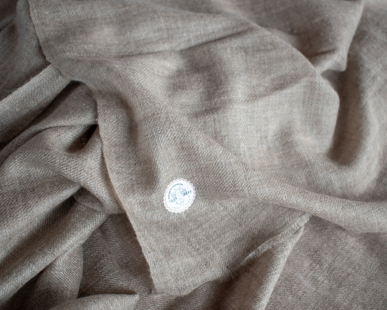 May include: A soft, light brown cashmere scarf with a small white tag that says "100% Cashmere".