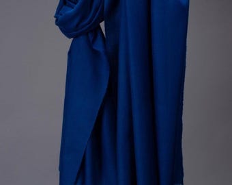 May include: A royal blue cashmere scarf with a fringed edge. The scarf is folded and draped over a gray background.