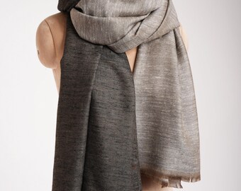 May include: A brown and grey ombre scarf with a fringed edge. The scarf is draped over a mannequin.