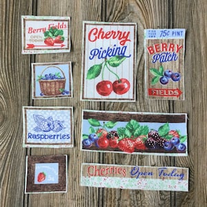 May include: A collection of fabric patches featuring various berry designs. The patches include images of strawberries, blueberries, raspberries, cherries, and a sign that reads "Berry Patch 75c Pint".