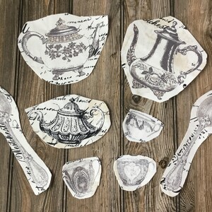 May include: A set of eight vintage-style tea party decorations, including teapots, cups, and a spoon, printed on white paper with black ink and featuring intricate designs.