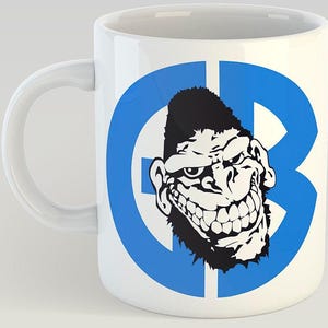 May include: White ceramic mug featuring a blue circle with a black and white illustration of a grinning monkey inside. The circle contains the letters "GB".