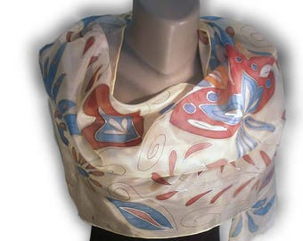 May include: A cream-coloured silk scarf with a hand-painted design featuring red, blue and orange floral motifs.