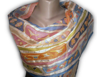 May include: A white silk scarf with a colourful geometric pattern in shades of blue, orange, pink, and yellow. The scarf is draped around a mannequin's neck.