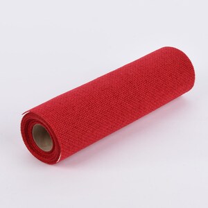 Può includere: Un rotolo di tessuto di juta rosso. Il tessuto è a trama fitta e ha un aspetto strutturato. Il rotolo è cilindrico, con l'estremità che mostra l'anima di cartone. Il colore è un rosso vibrante e uniforme.