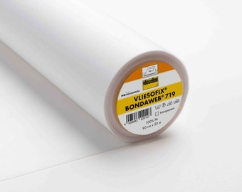 May include: A roll of white Vliesofix® Bondaweb® 719 iron-on adhesive web. The circular label features the brand name, a barcode, care symbols, 100% PA composition, and the dimensions 90 cm x 30 m. The adhesive material is semi-transparent.