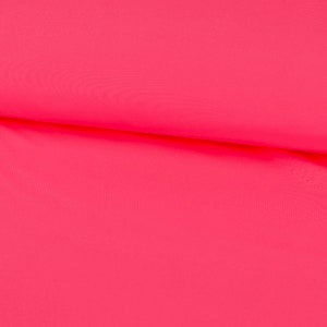 Pode incluir: Um tecido rosa brilhante com uma textura lisa. O tecido está dobrado ao meio, mostrando o interior da dobra.