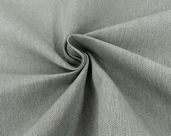Könnte beinhalten: Nahaufnahme eines grauen, strukturierten Stoffes mit einem dezenten weißen Muster. Der Stoff ist gefaltet und drapiert und zeigt seine weiche und glatte Textur.