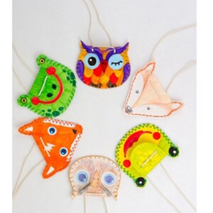 May include: Six felt animal necklaces with colourful details. The necklaces feature a green frog, an orange fox, a yellow car, a brown owl, a white bird, and a pink fox.