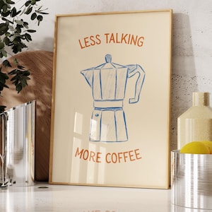 Könnte beinhalten: Ein gerahmter Druck mit hellbeigem Hintergrund zeigt eine blaue Strichzeichnung eines Espressokochers. Die Worte "LESS TALKING" und "MORE COFFEE" sind in Orange gedruckt. Der Druck wird auf einer weißen Arbeitsplatte ausgestellt.
