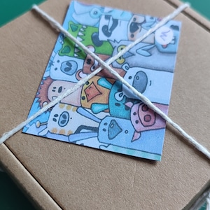 May include: A brown cardboard box with a white string tied around it. The box has a colorful sticker on it with a cartoon image of a group of animals. The sticker has the letter "M" written on it.