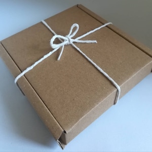 May include: A brown cardboard box tied with white twine, creating a simple and elegant gift presentation.