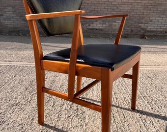 May include: A mid-century modern armchair with a dark blue leather seat and backrest. The chair has a wooden frame with armrests and a slightly curved back. The chair is made of wood and leather.