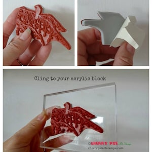 May include: A red rubber stamp with a detailed design of a bird with branches. The stamp is on a white background and is being held by a hand. The text "Cling cushioned stamp" is above the stamp. The text "Peel off the backing" is above a second image of the stamp with the backing being peeled off. The text "Cling to your acrylic block" is above a third image of the stamp being placed on a clear acrylic block. The text "OCHERRY PIE Art Stamps" and "cherrypieartstamps.com" is below the stamp.