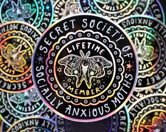 May include: A holographic sticker with a black background and rainbow iridescent foil. The sticker features a moth with a white body and black wings, surrounded by a circle that reads "Secret Society of Socially Anxious Moths" and "Lifetime Member".