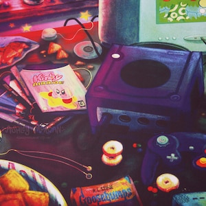 以下が含まれることがあります： 紫色の任天堂ゲームキューブ本体とコントローラー、そして「カービィエアライド」というラベルのついたゲームカートリッジ。本体の周りには、シリアルボックス、ポテトチップスの袋、コンピューターモニターなど、さまざまなアイテムが置かれている。
