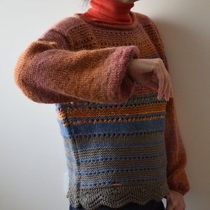 May include: A multi-colored striped sweater with a scalloped hem. The sweater is knit in a variety of shades of brown, orange, blue, and gray.