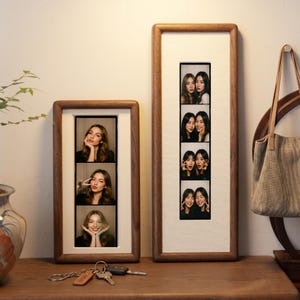 two framed photographs of smiling women, placed on a wooden surface next to a set of keys.