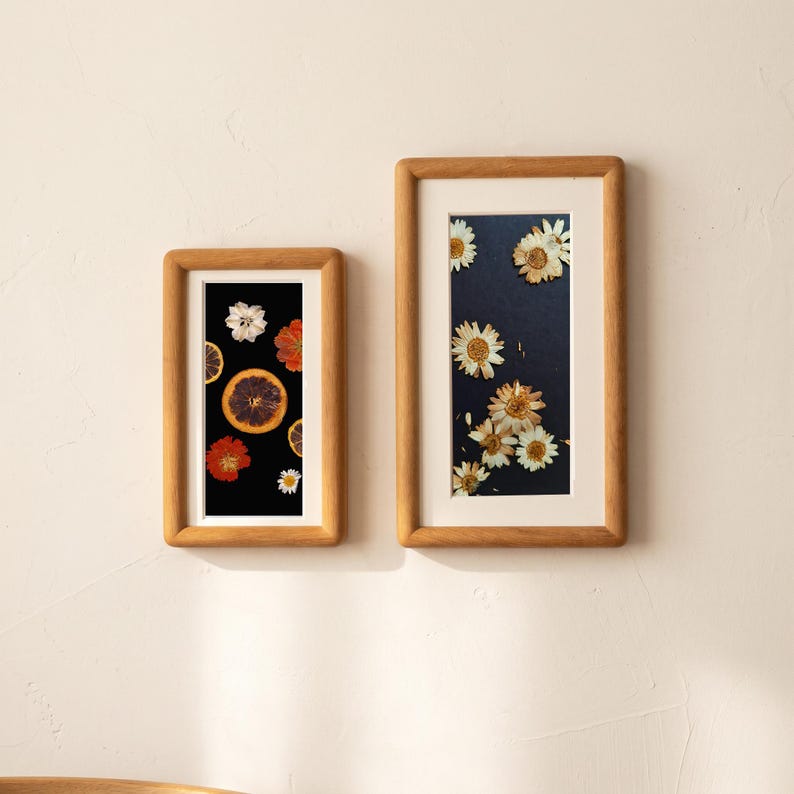 two framed pictures hanging on a white wall. The left frame contains a collage of various flowers, including daisies, roses, and lilies, arranged in a visually appealing manner. The right frame showcases a close-up of a flower, highlighting its intricate details and vibrant colors.