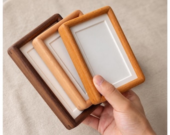 May include: Three rectangular wooden picture frames stacked together, featuring varying wood tones from dark brown to light tan. Each frame has a smooth, rounded edge and a plain white rectangular insert centered within the frame's opening.