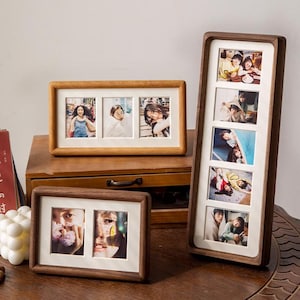May include: Three wooden photo frames with multiple openings, each holding photographs. The frames are in various sizes and orientations, with a light wood finish and white matting. The photos depict people.