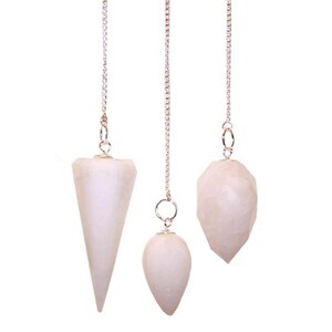 May include: Three white crystal pendulums suspended from silver chains. The pendulums are shaped as a cone, an egg, and a faceted teardrop. The crystals are a pale, translucent colour, and the chains are delicate.