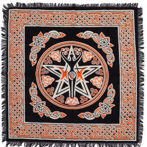 May include: Black square textile with an orange and white Celtic knot design. The centre features a white star with an orange figure inside a circle. The border has a repeating knot pattern, and the edges are fringed.