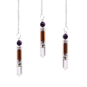 May include: Three crystal pendulums suspended from silver chains. Each has a clear crystal point, a brown wooden centre, silver metal detailing, and a purple gemstone at the top.