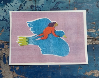 May include: A print featuring a person riding a large blue bird against a pink background. The bird has a yellow beak and green tail feathers. The person is wearing an orange jumpsuit and has brown hair.