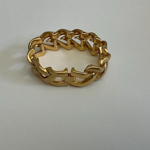 May include: A gold-colored bracelet with a chain-link design. The bracelet is made of metal and has a clasp closure. The links are shaped in a repeating pattern.