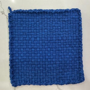 May include: A square, woven potholder in a vibrant blue hue. The potholder has a looped corner for hanging and a tightly woven texture. This kitchen textile is designed to protect hands from hot cookware.